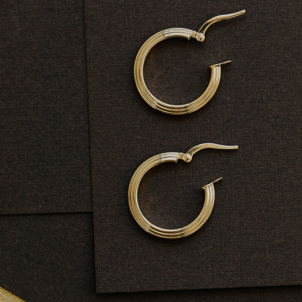 Gold hoop earrings on a dark brown surface