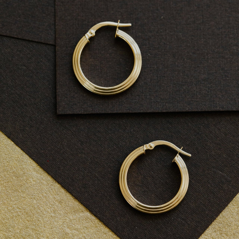 Gold hoop earrings on a black and beige surface