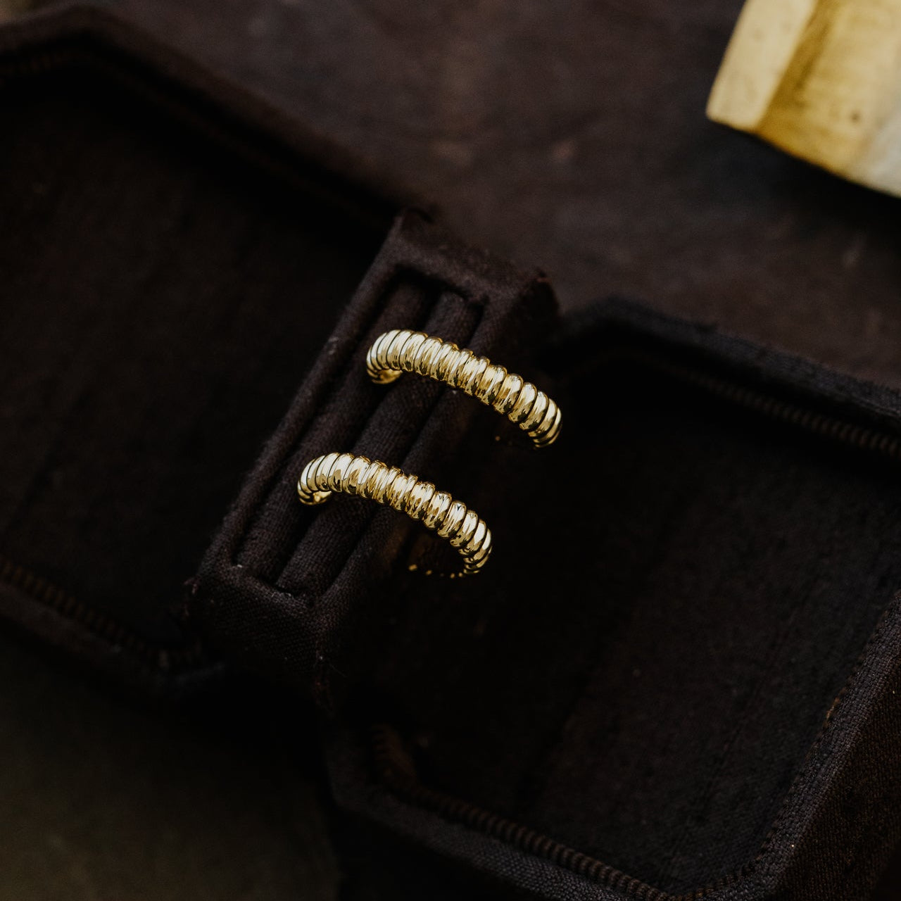 Gold earrings on a black jewelry box