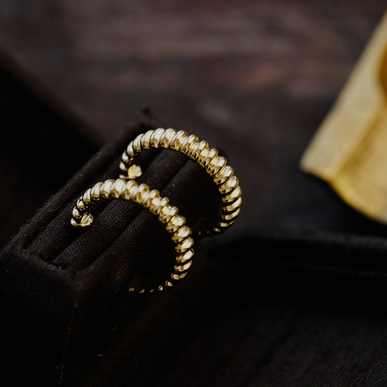 Gold earrings with a unique design on a dark background