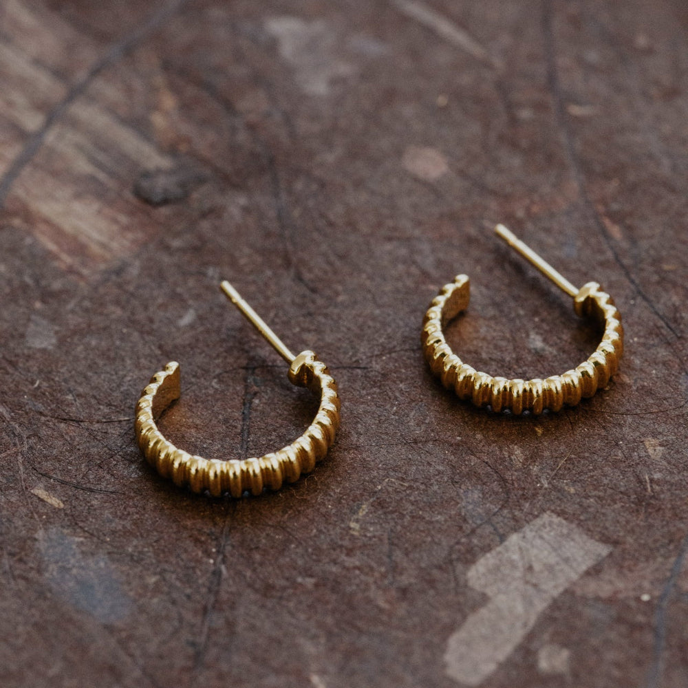 Gold hoop earrings on a textured brown surface