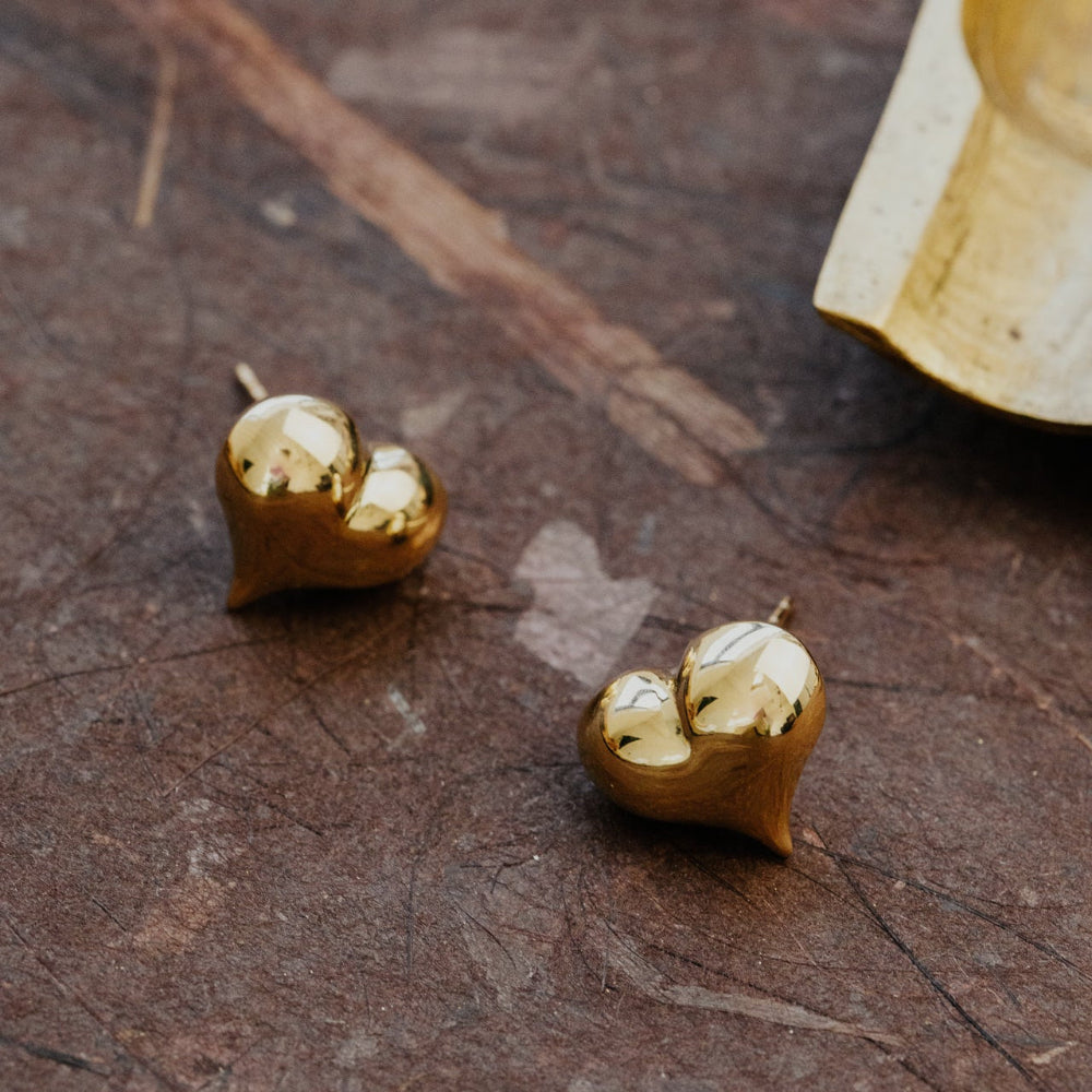 Gold heart-shaped earrings on a wooden surface