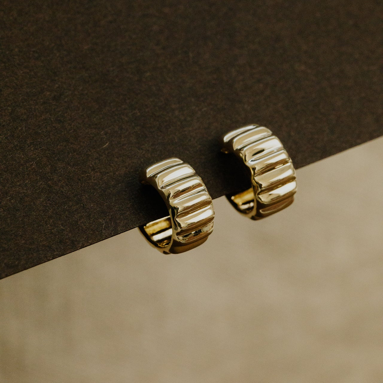 Gold hoop earrings on a brown surface
