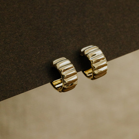 Gold hoop earrings on a brown surface