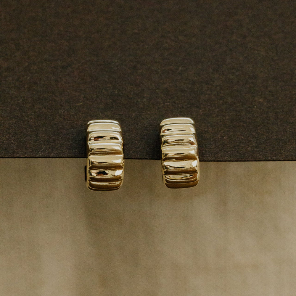 Gold hoop earrings on a dark surface