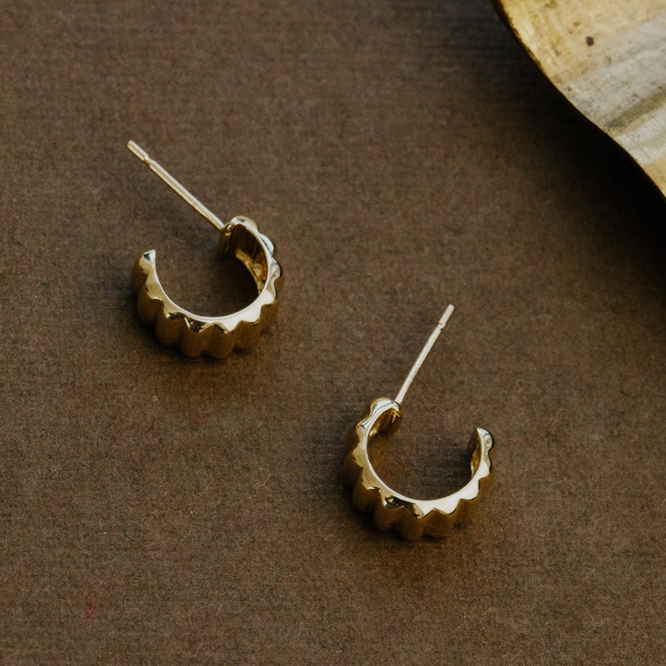 Gold hoop earrings on a brown surface