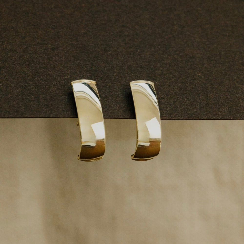 Gold hoop earrings on a brown surface