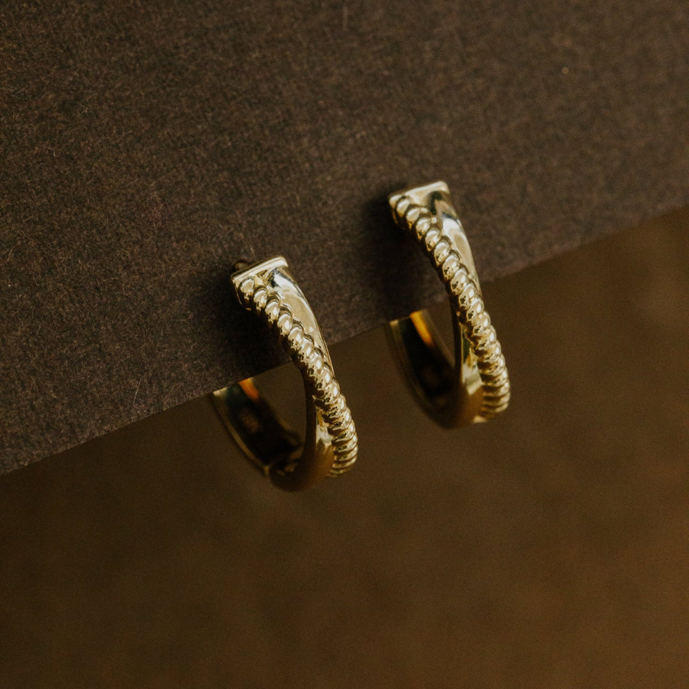Gold hoop earrings on a dark brown surface