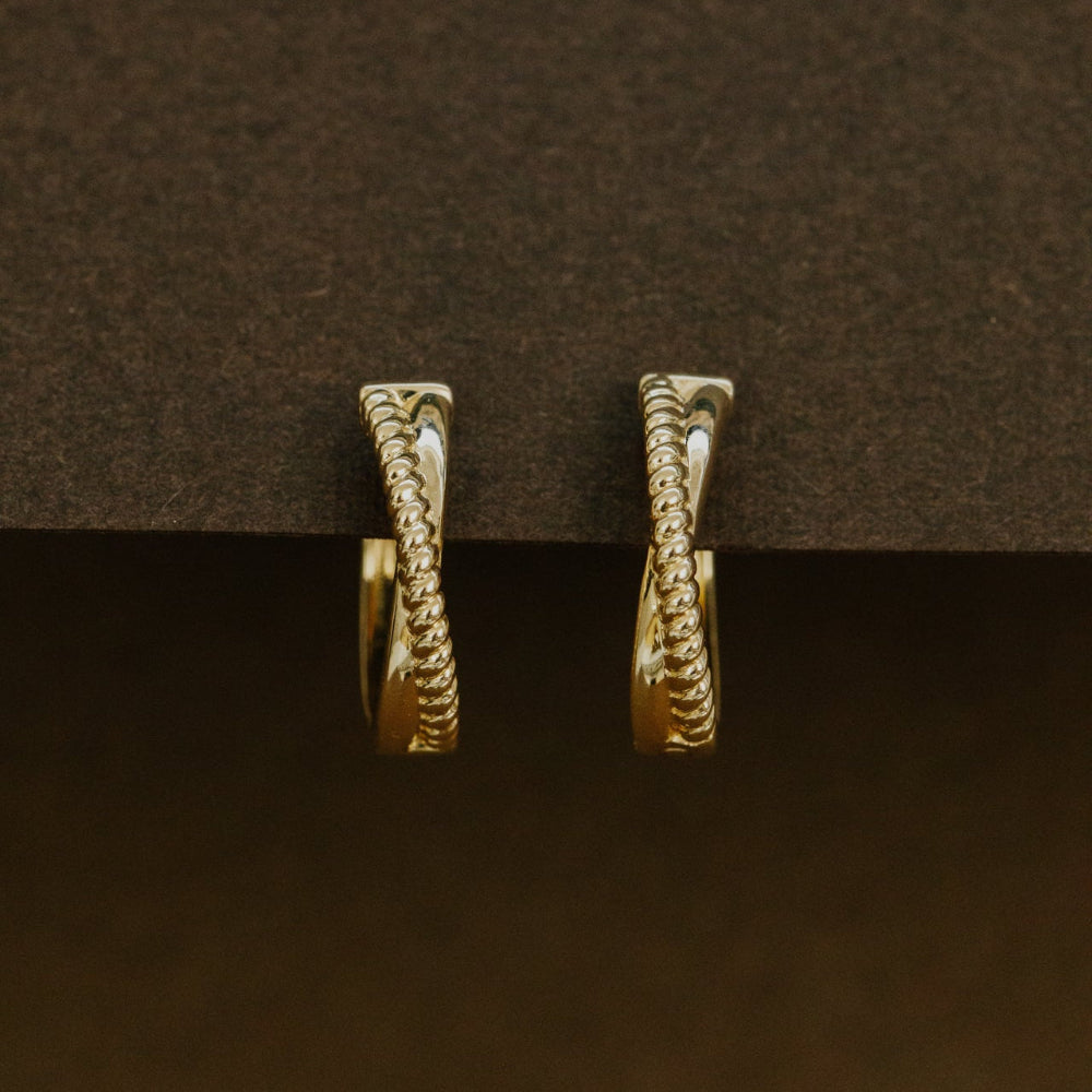 Pair of gold hoop earrings on a dark brown background