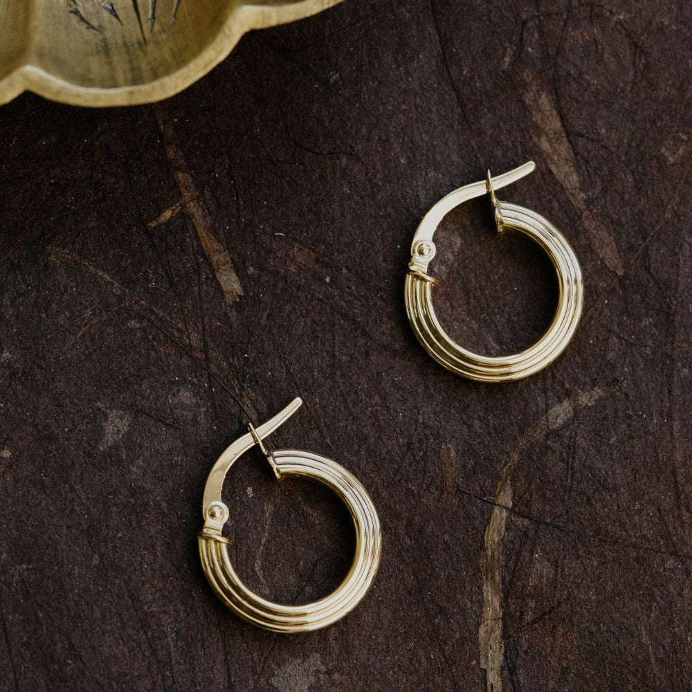 Gold hoop earrings on a dark textured surface