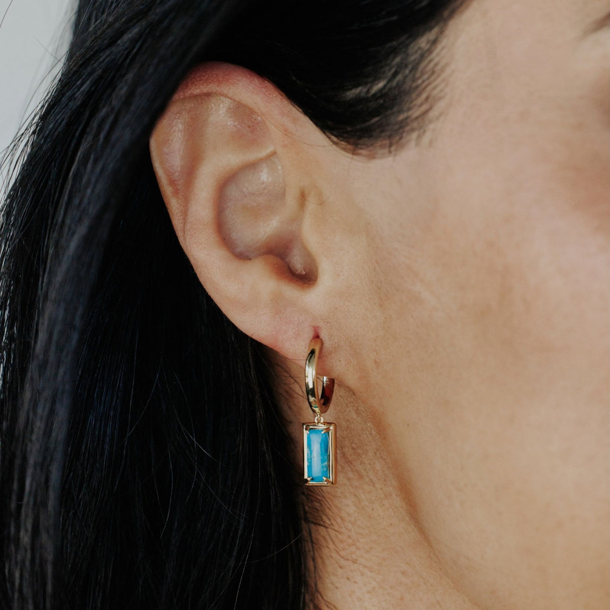 14k yellow gold rectangle turquoise dangle hoop earrings showcased on a model.