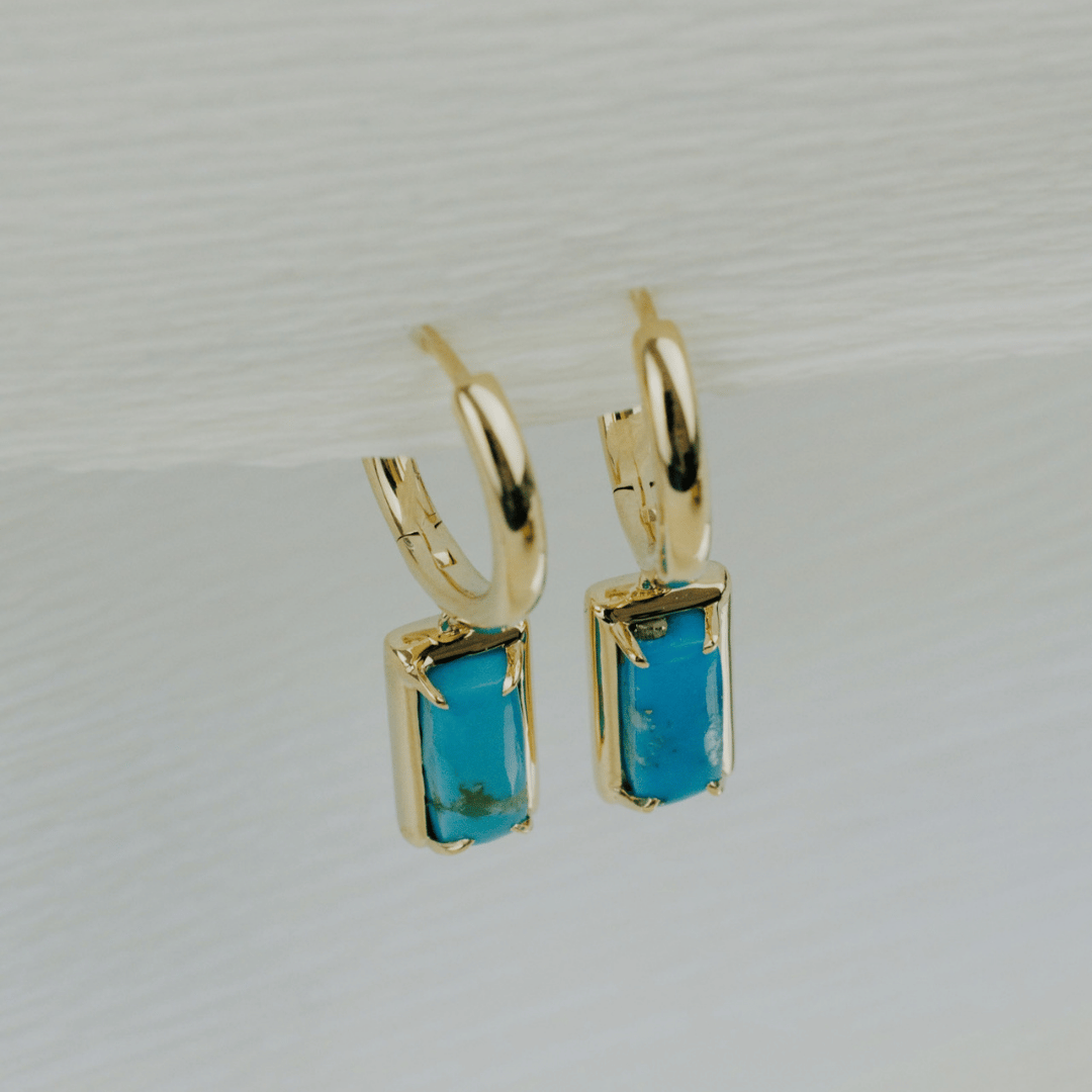 14k gold rectangle turquoise dangle hoop earrings on a textured white background. 