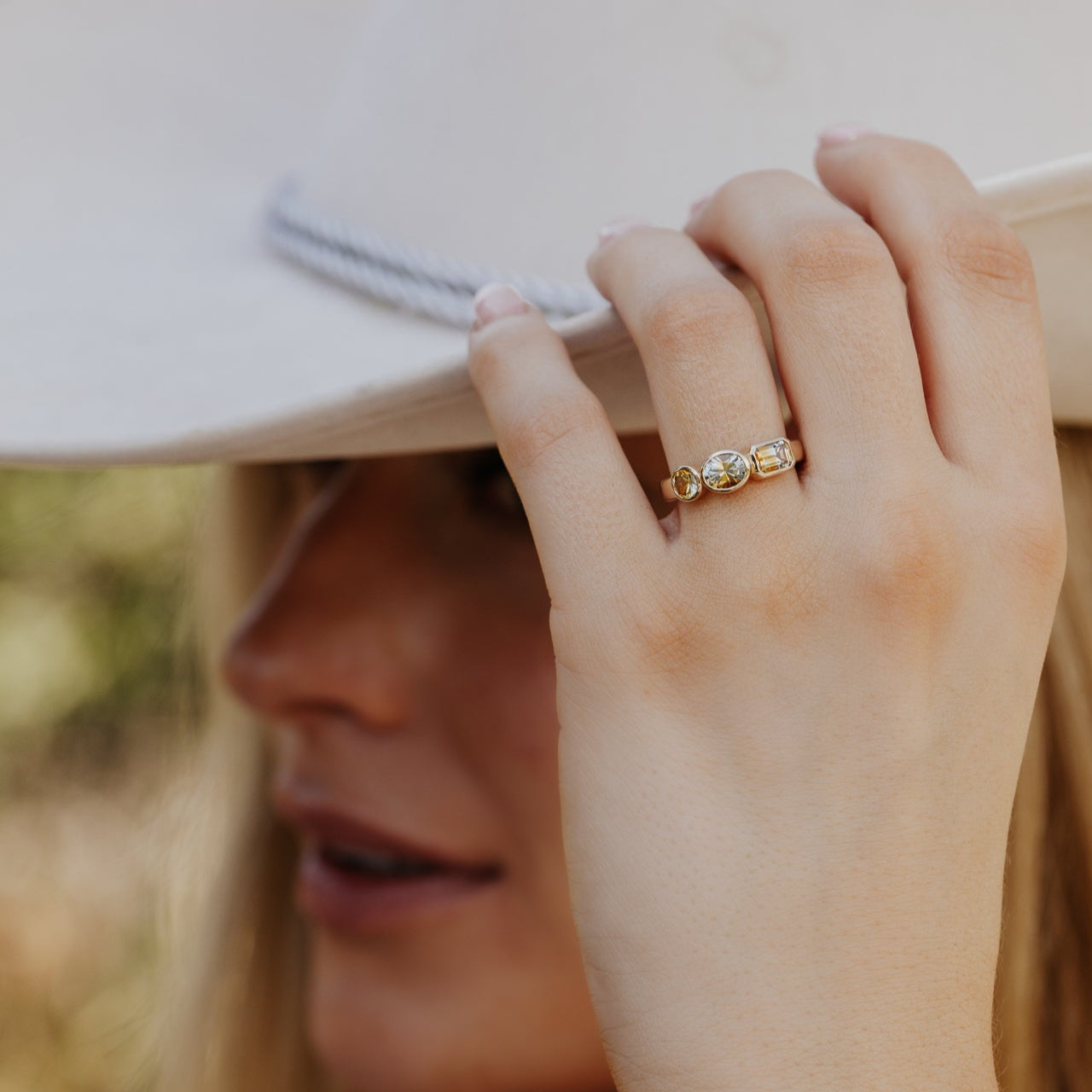 Close-up of a hand wearing a gold ring with a blurred background