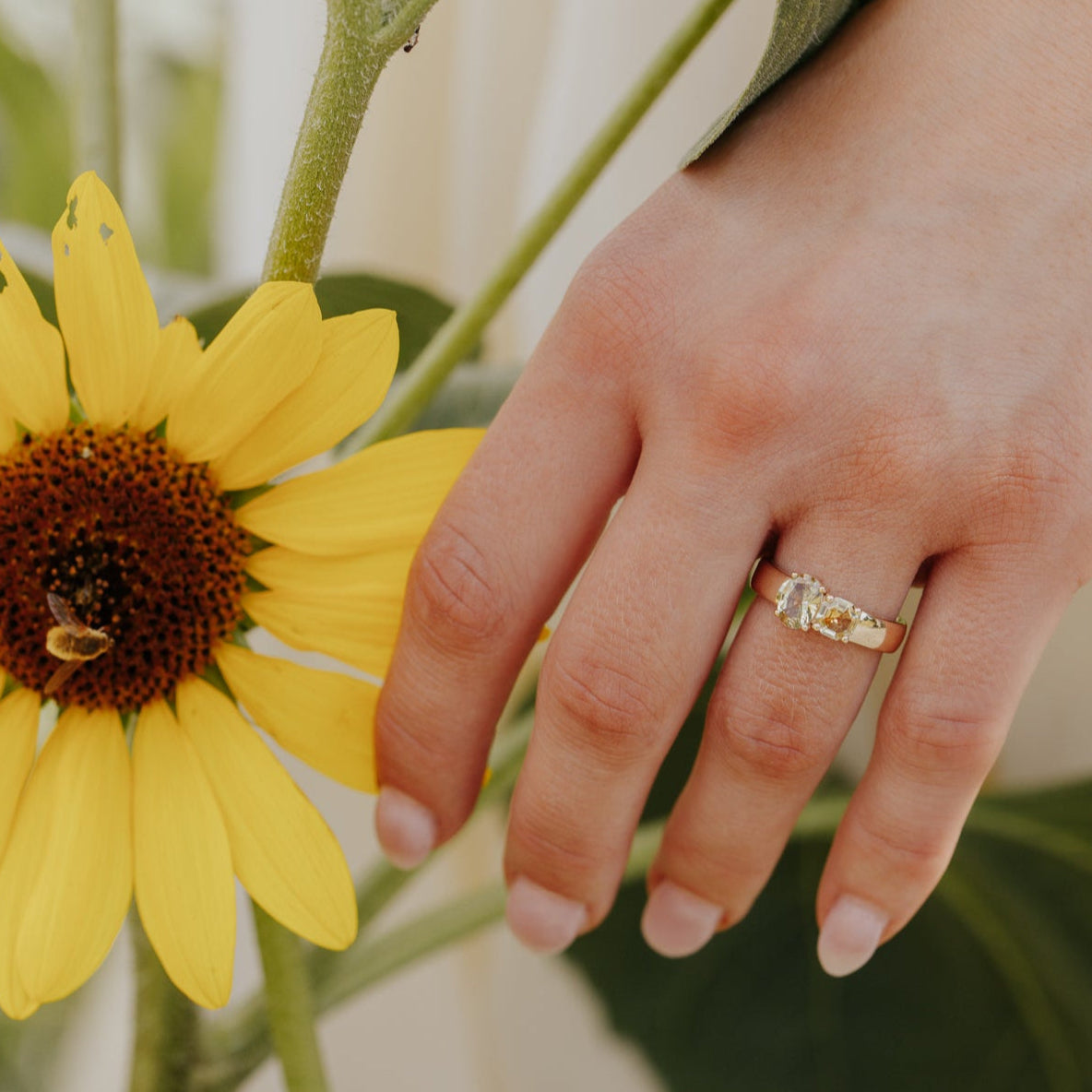 Hand with a ring with Montana sapphires near a sunflower