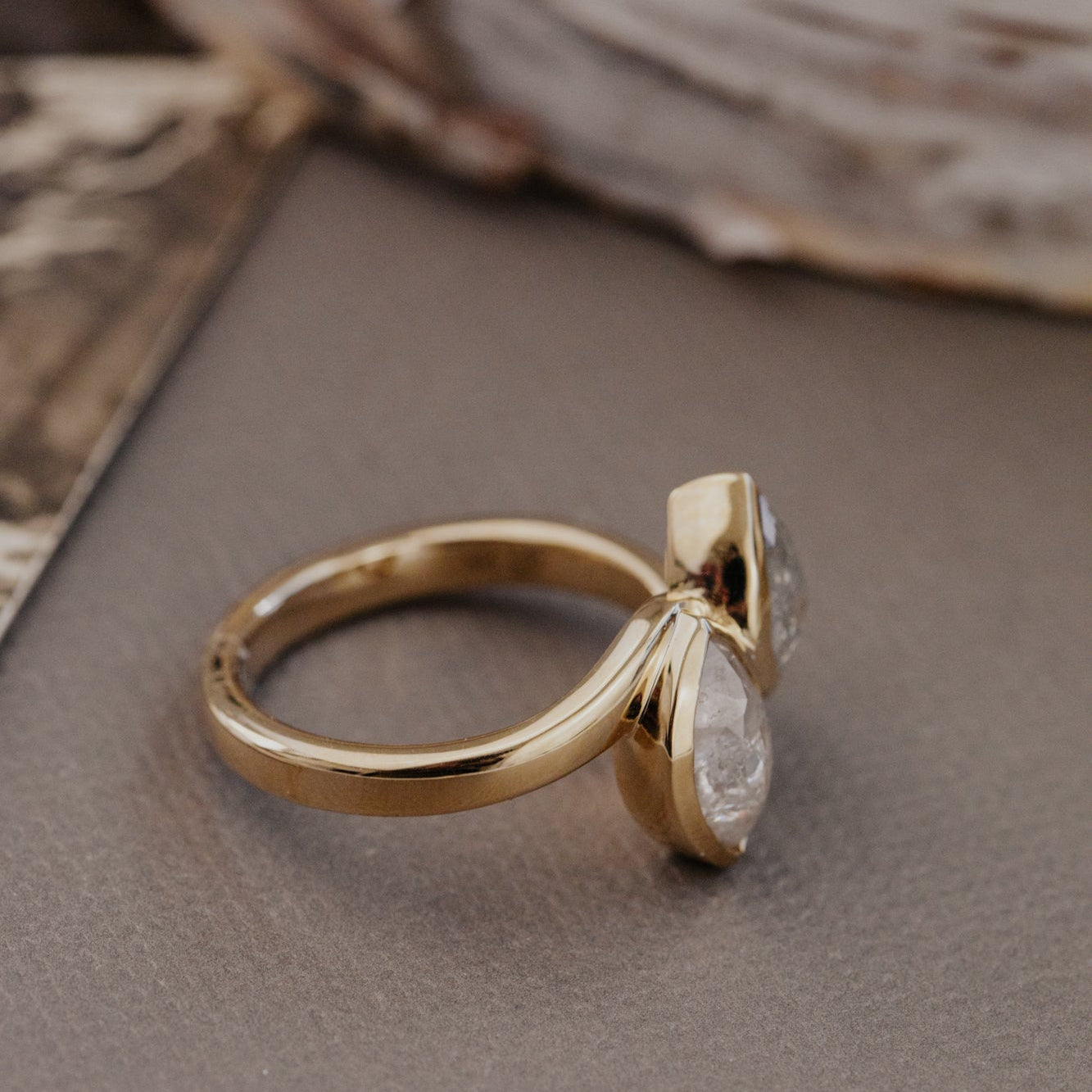 Gold ring with a rustic diamond on a textured surface.
