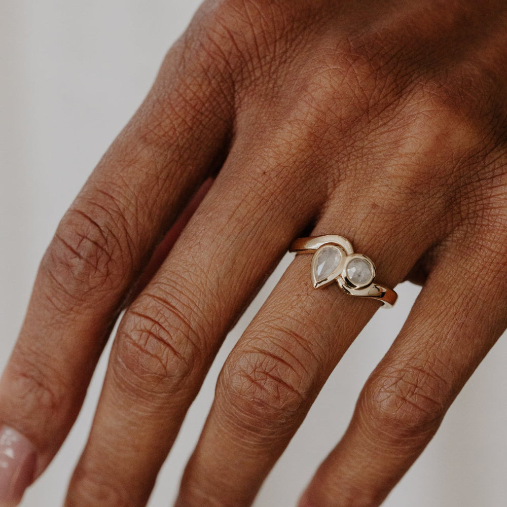 Hand wearing a Holland ring with a rustic diamonds on a neutral background.