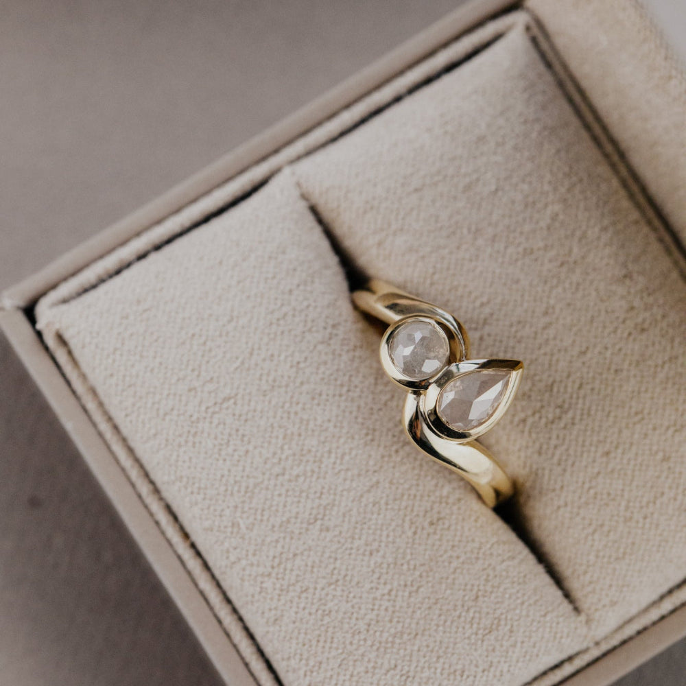 Gold Holland ring with rustic diamonds in a beige jewelry box on a light gray surface.