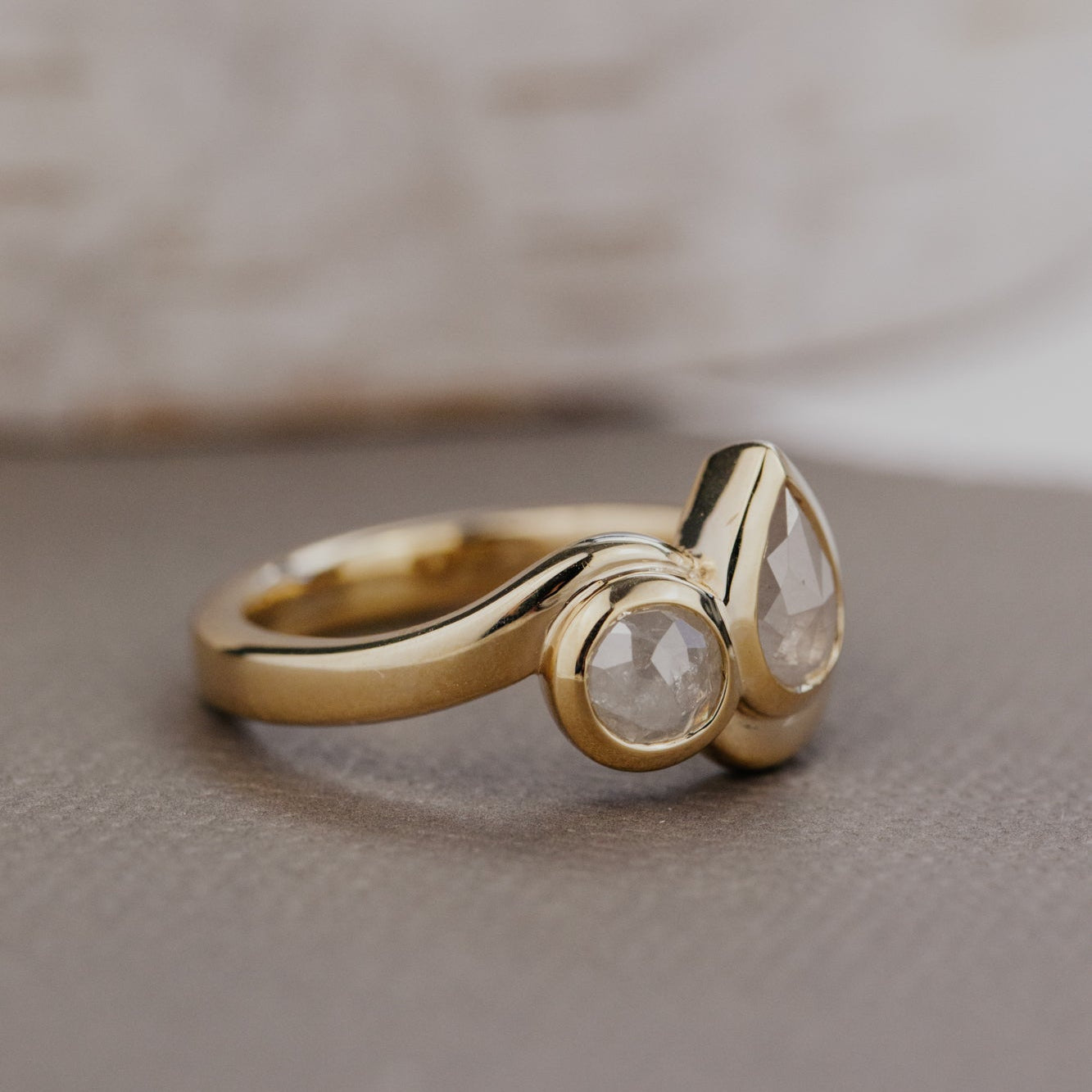 Gold ring with a clear rustic diamonds on a textured surface.