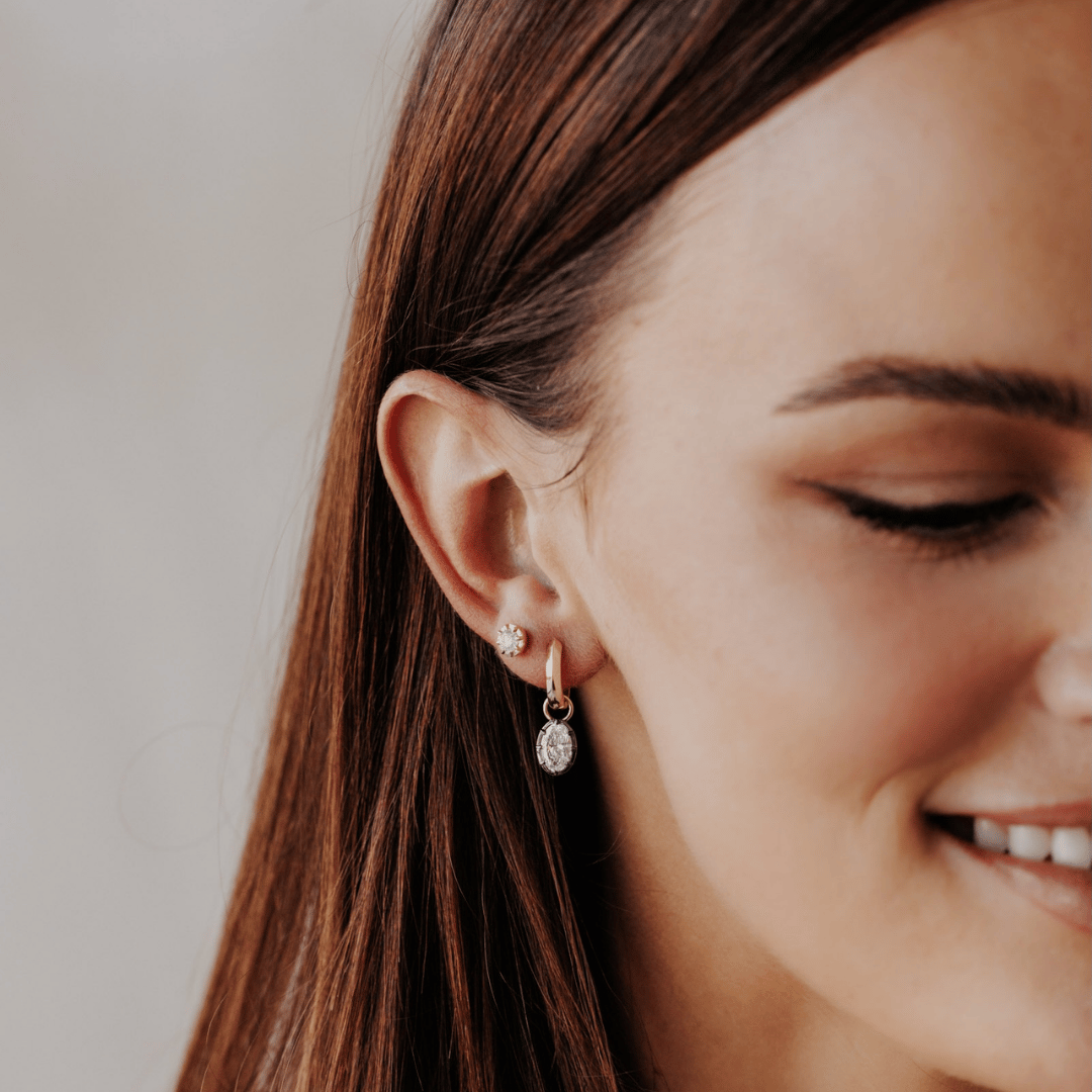 14k gold round cut, lab grown diamond dangle earrings with Black Rhodium featured on the ear of a model. 