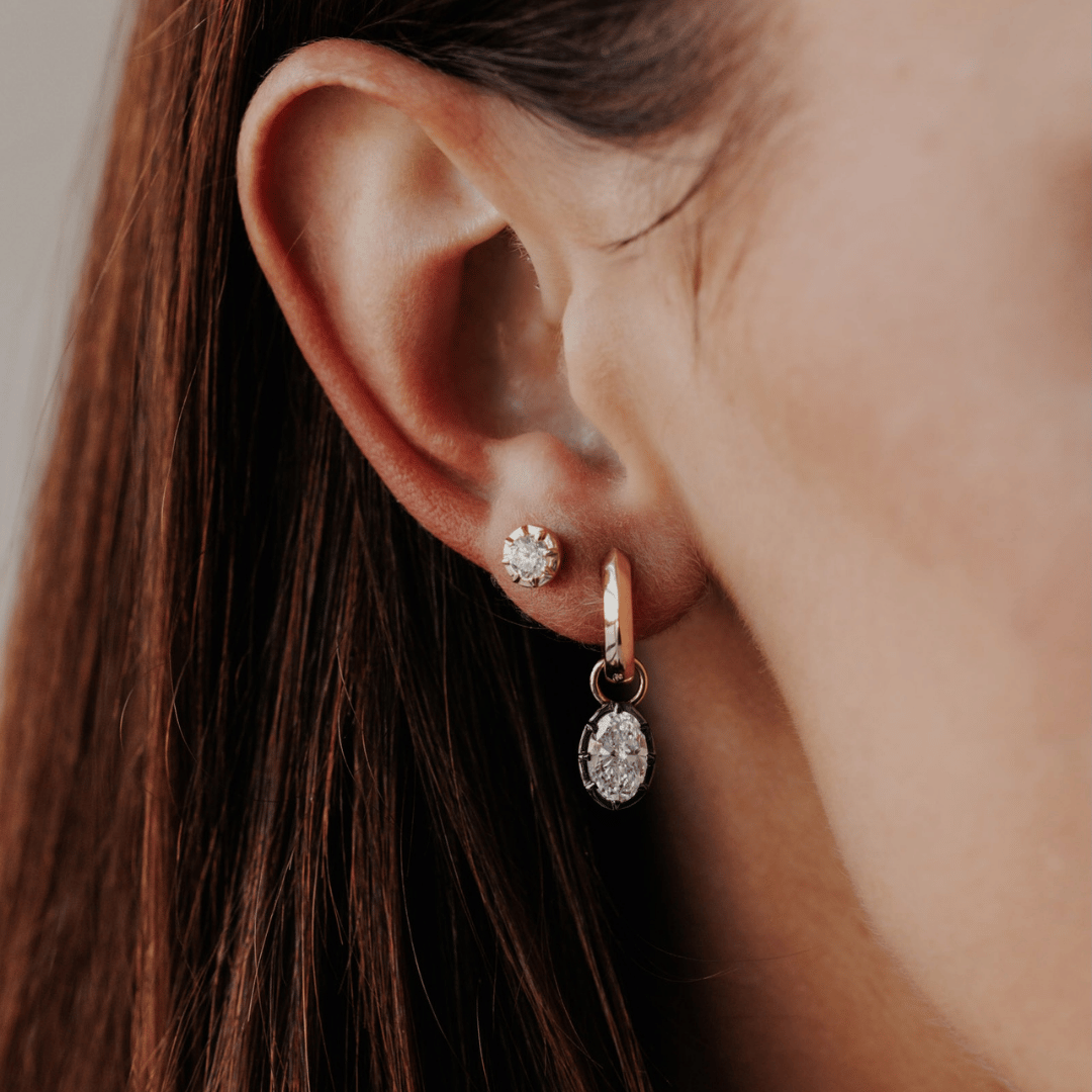 14k gold round cut, lab grown diamond dangle earrings with Black Rhodium featured on the ear of a model. 