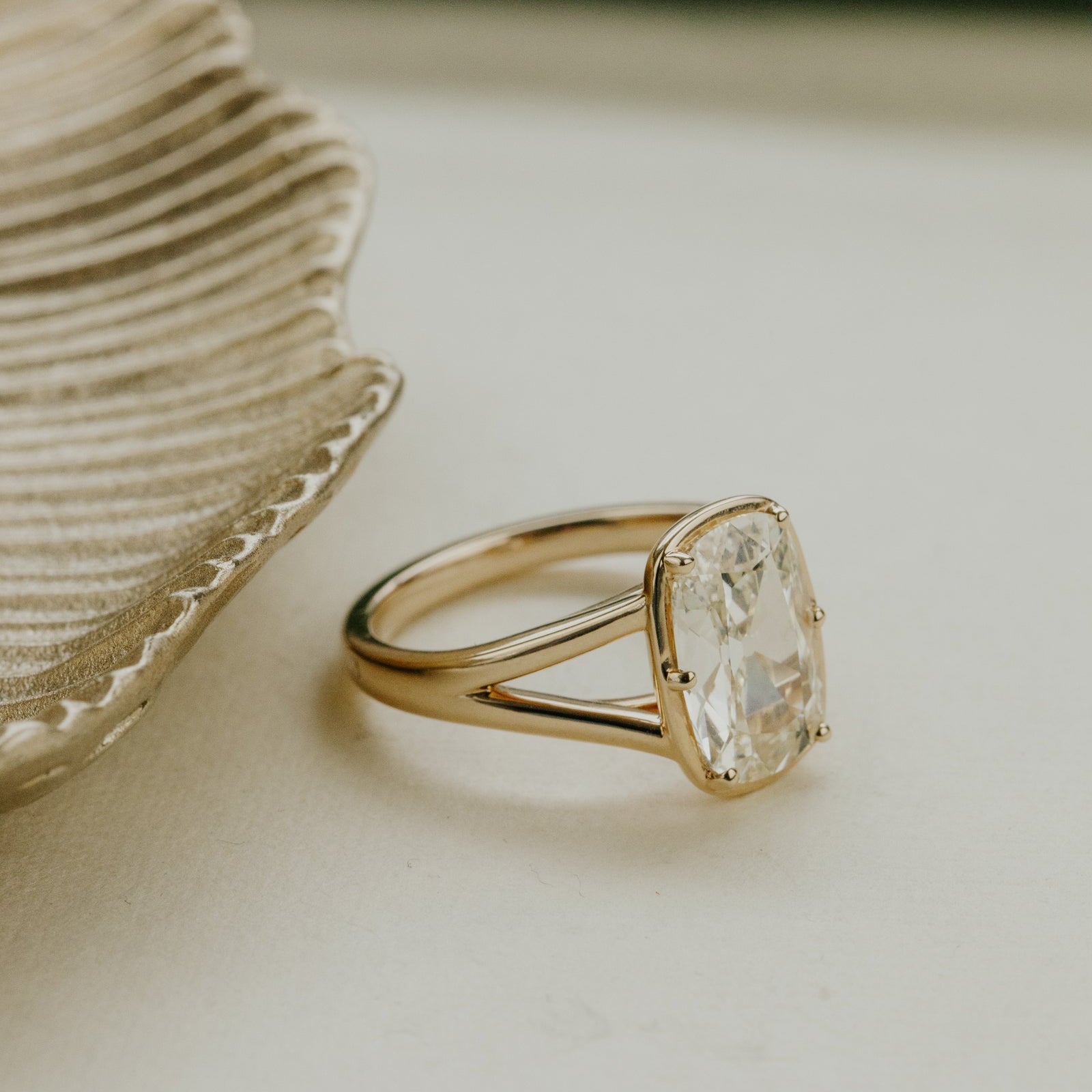 Gold ring with a elongated old mine cut antique diamond on a light surface.