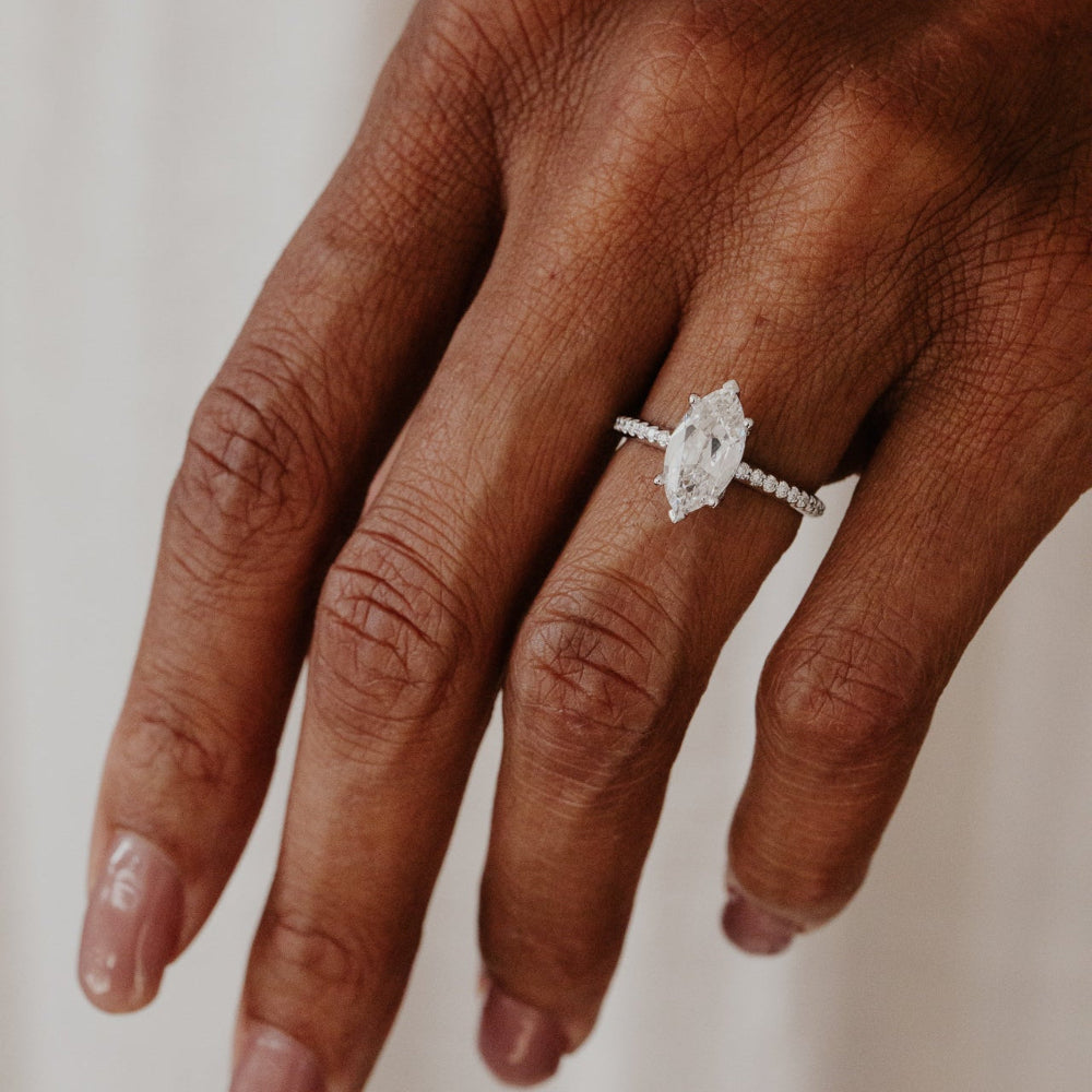 Hand wearing a old mine cut marquise lab grown diamond ring on a neutral background.