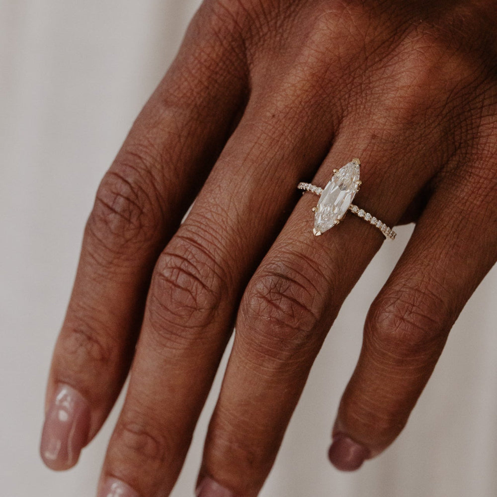 Hand wearing a lab grown diamond ring on a neutral background.