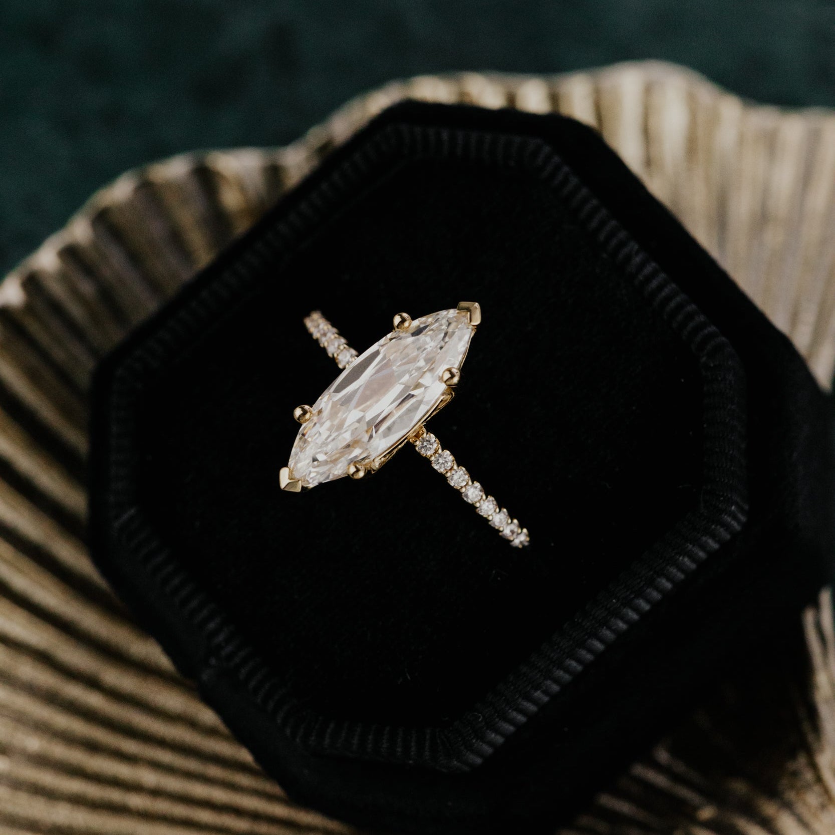 Lab grown diamond ring in a black velvet box on a textured surface with blurred green background.