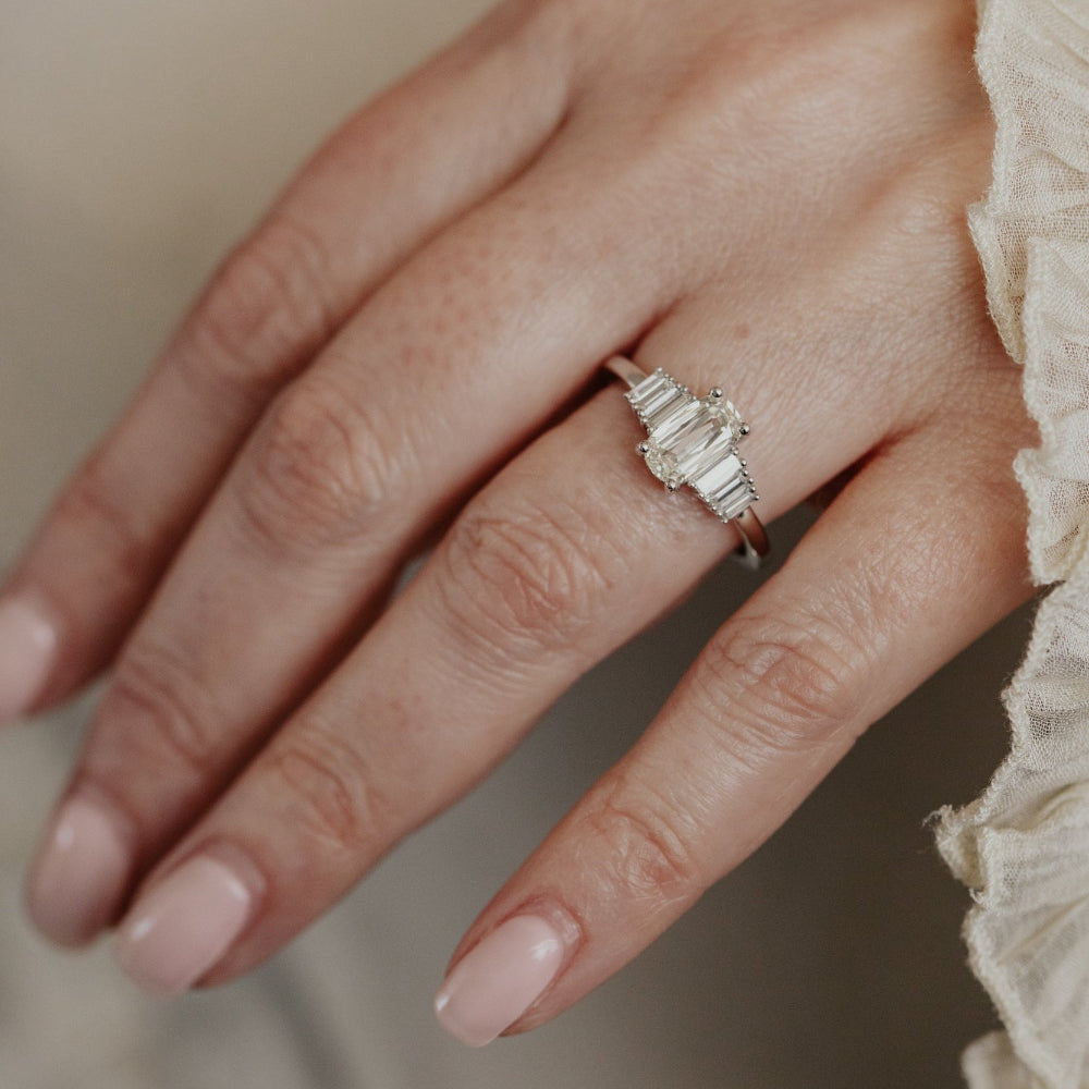 Close-up of a hand wearing a elongated cushion diamond ring with a neutral background.