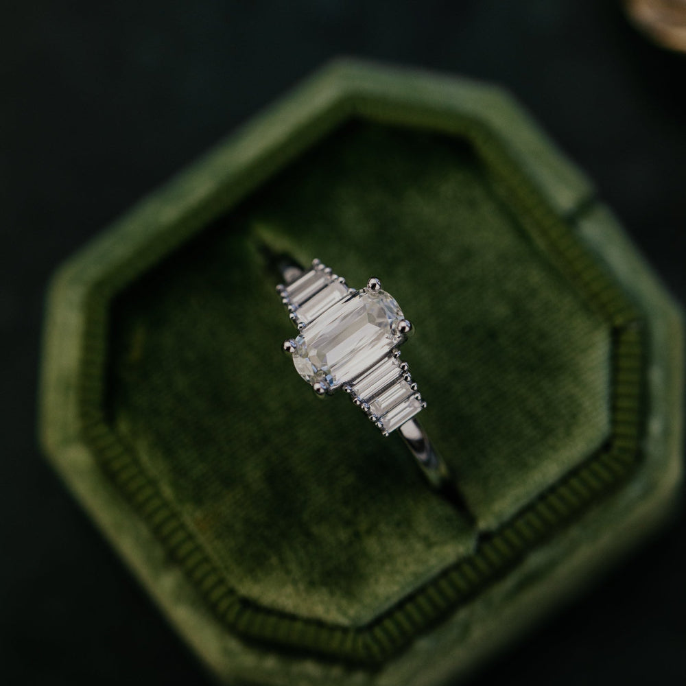 Diamond ring in a green velvet box on a dark background.