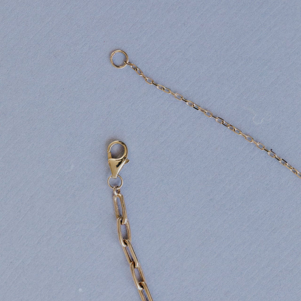 Gold chain necklace with clasp on a light blue background
