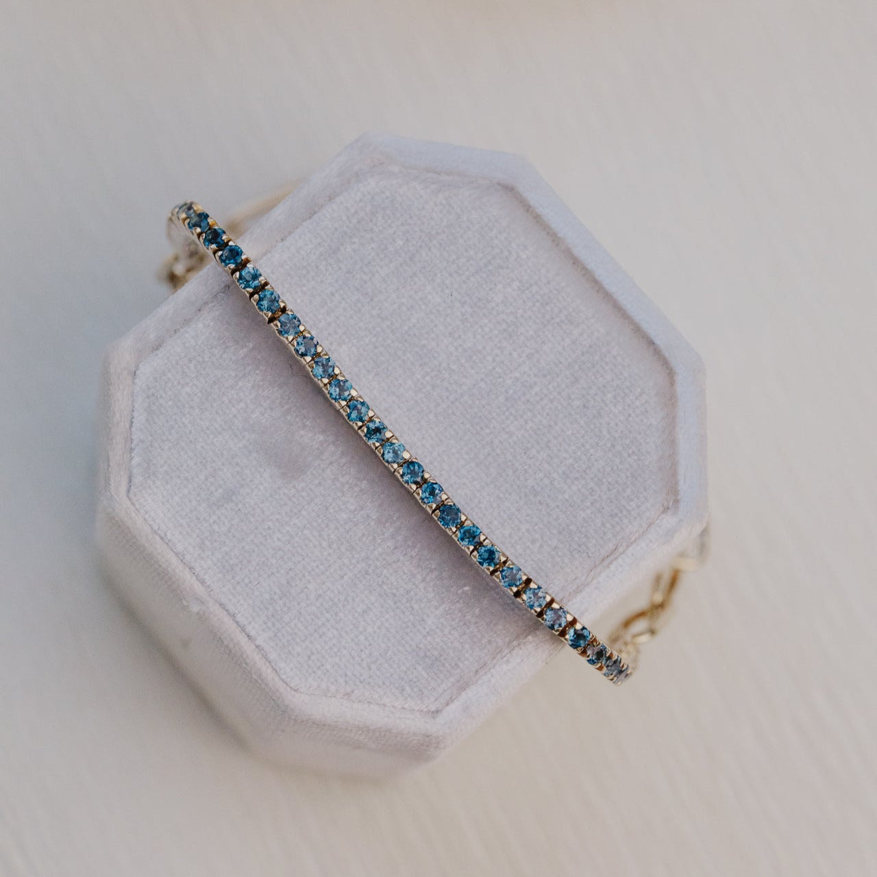 Bracelet with blue topaz stones on a hexagonal white pillow