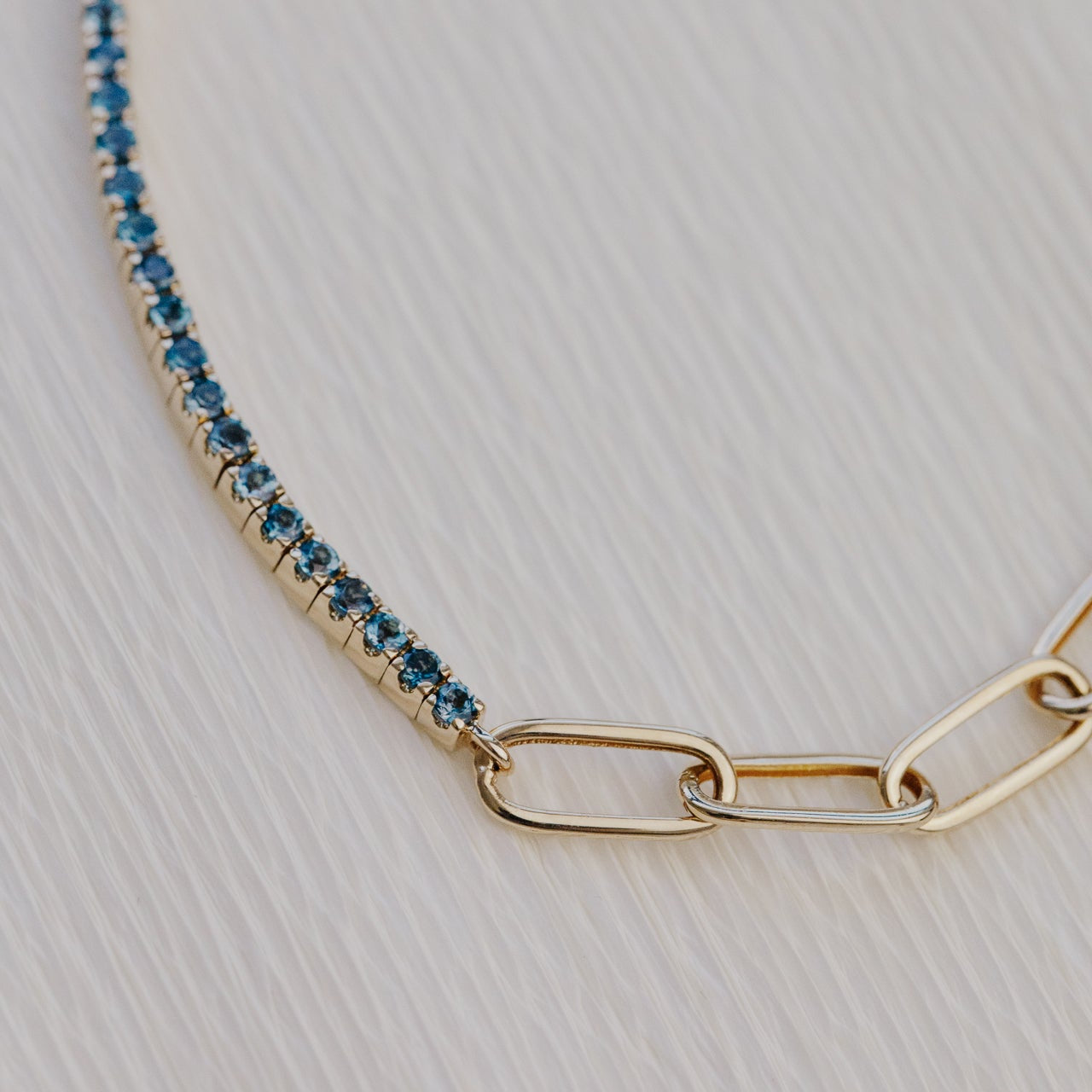 Gold bracelet with blue topaz gemstones on a light gray background