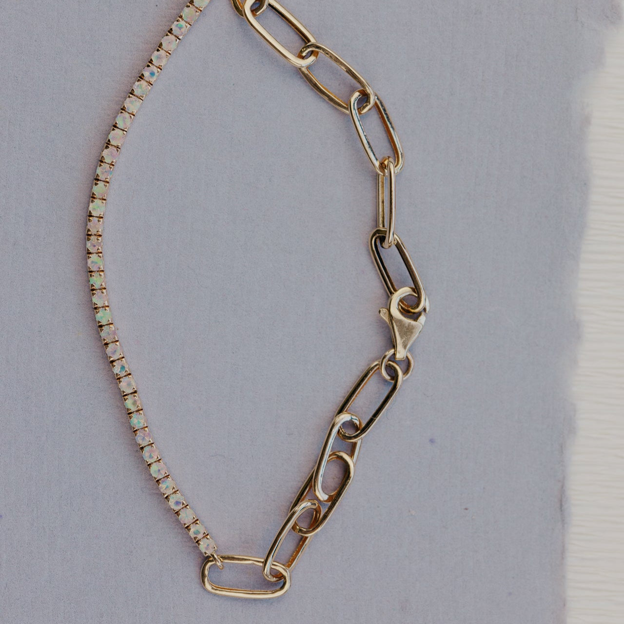 Gold chain bracelet with a clasp on a light gray background