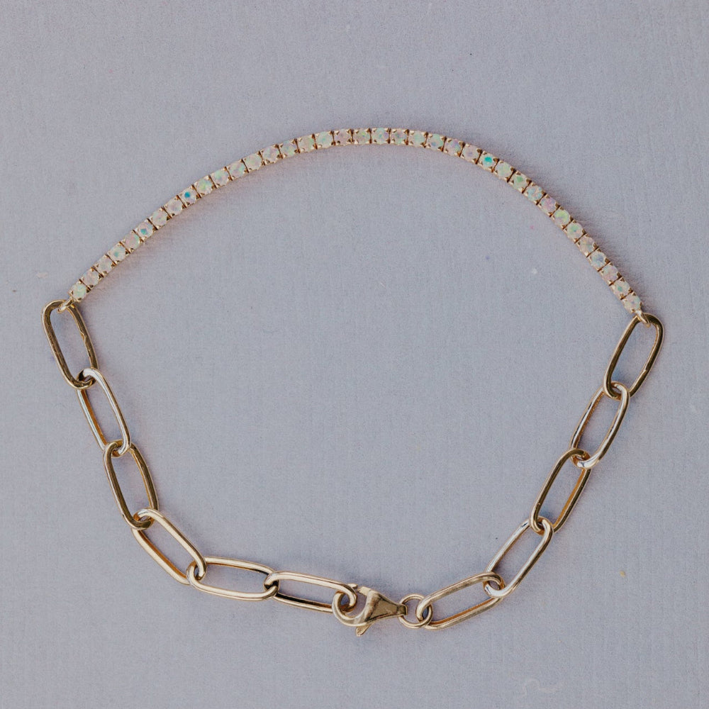 Gold chain bracelet with opals on a light gray background