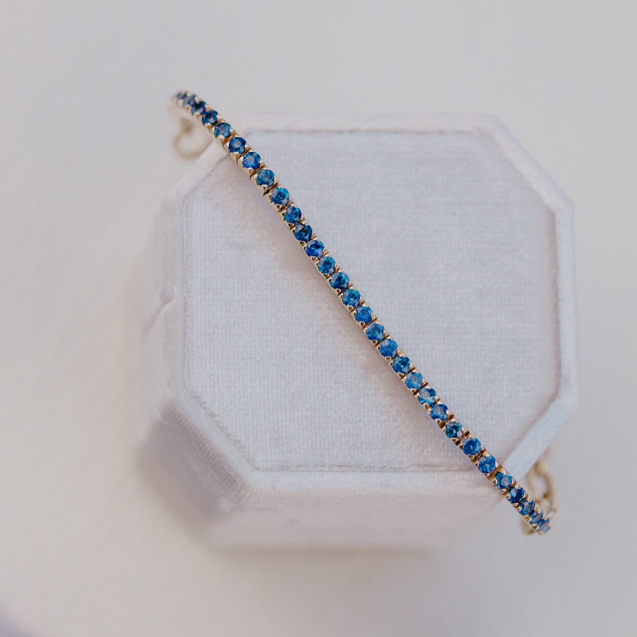 Blue sapphire gemstone bracelet on a white hexagonal stand