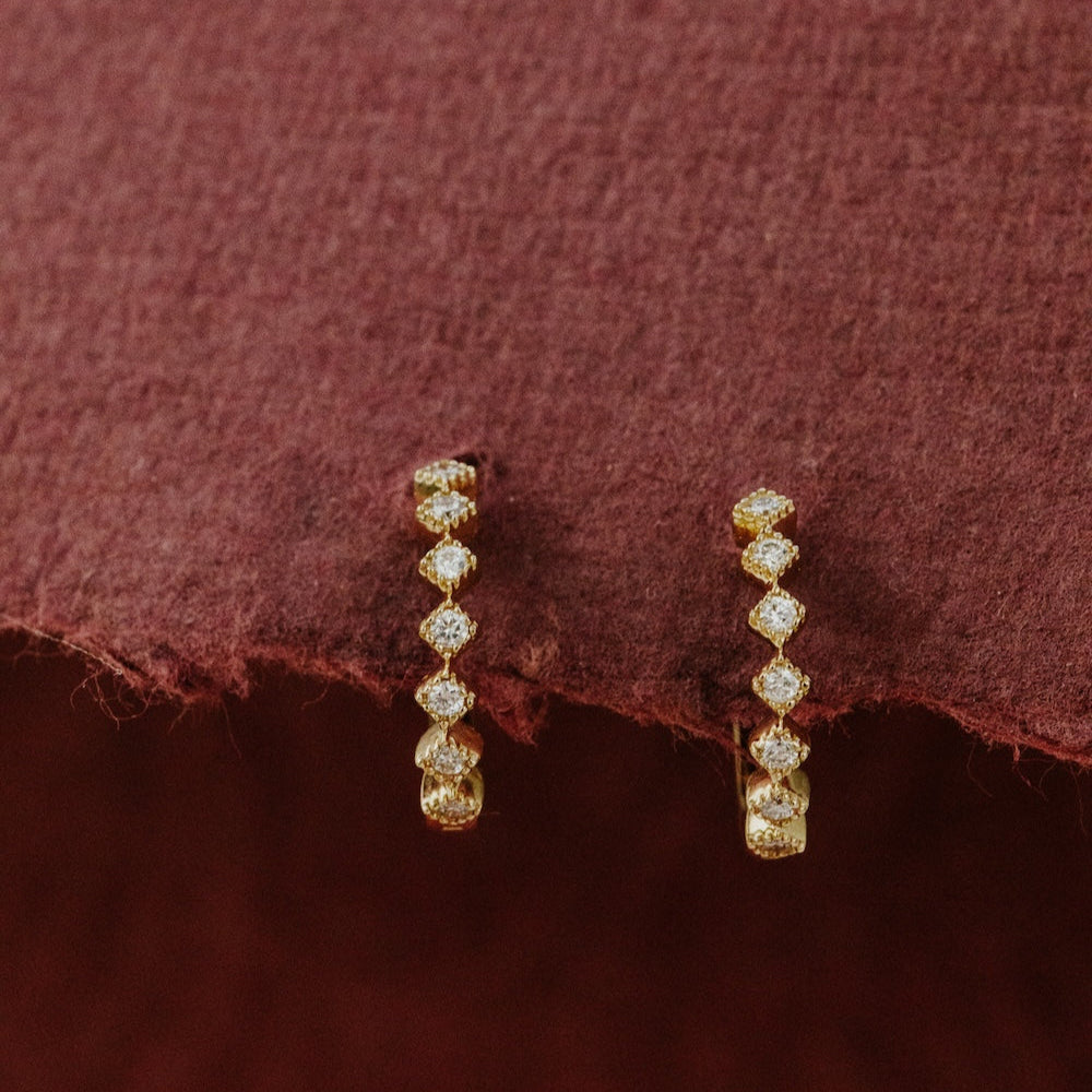 Pair of diamond hoop earrings on a textured red fabric background