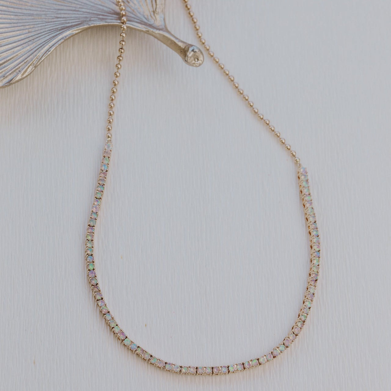 Delicate gold opal necklace with small beads on a light background