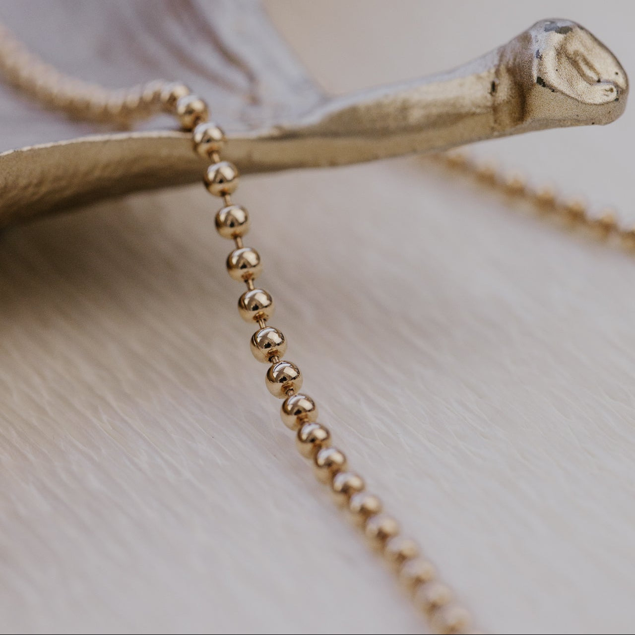 Gold beaded necklace on a wooden surface