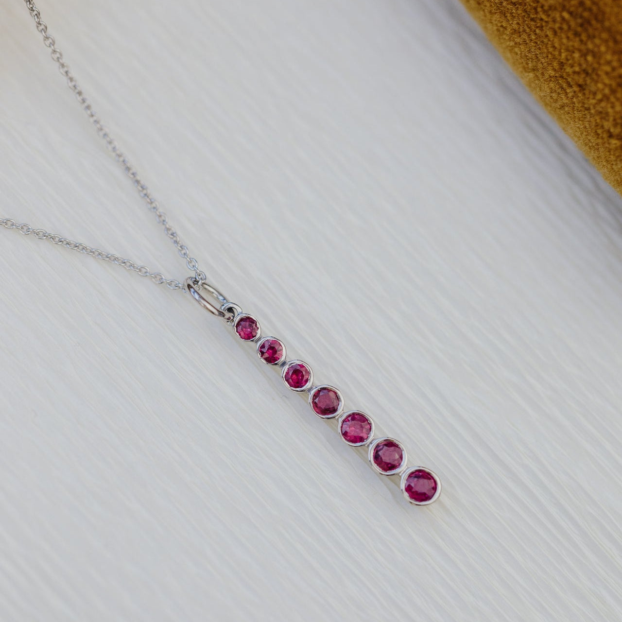Necklace with red gemstones on a textured white surface