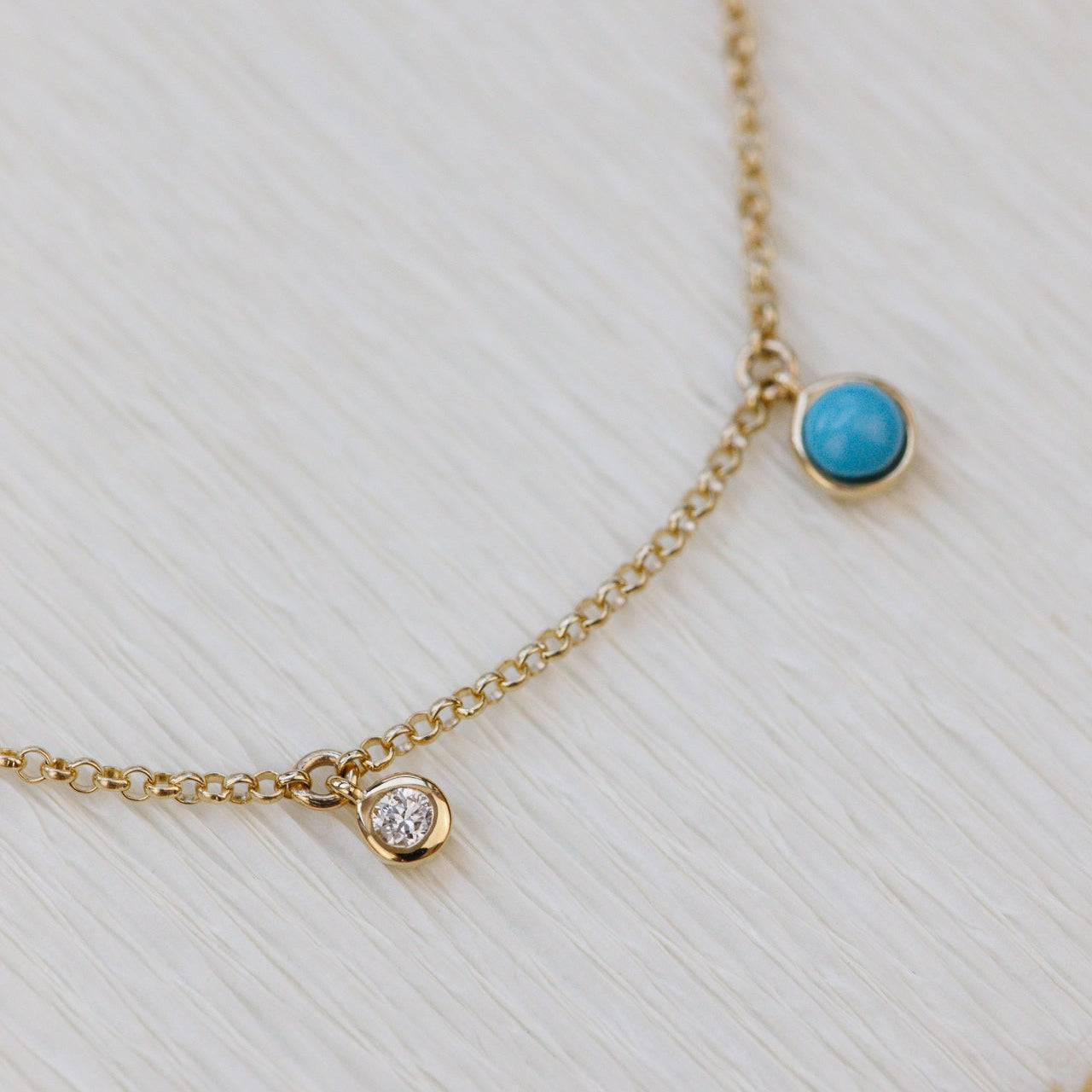 Gold necklace with turquoise and diamond gemstones on a light background