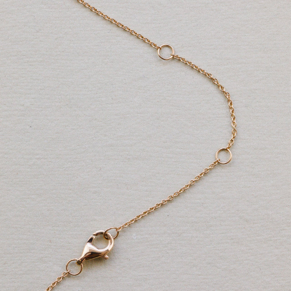 Gold chain necklace with clasp on a light gray background