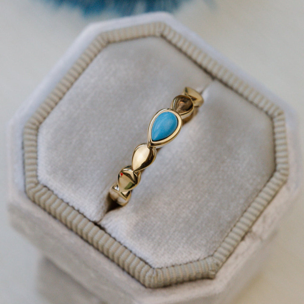 Gold ring with a blue turquoise stone on a velvet cushion