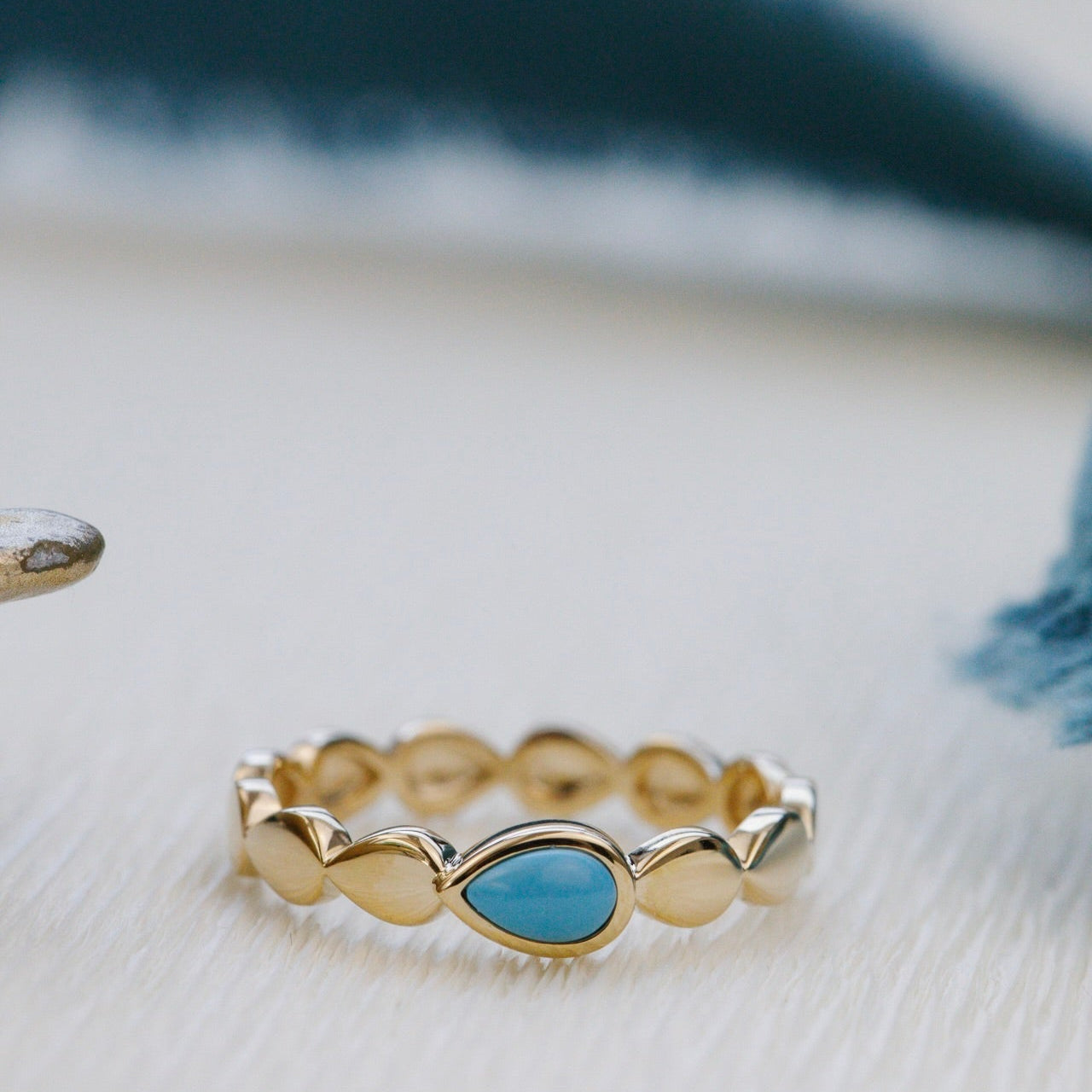Gold ring with a turquoise stone on a light surface