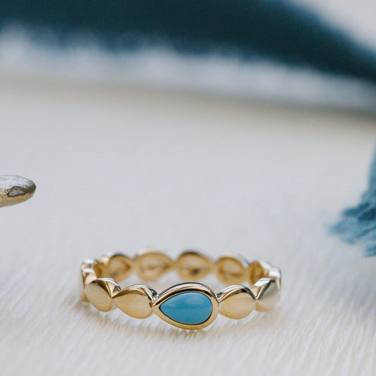 Gold ring with a turquoise stone on a light surface