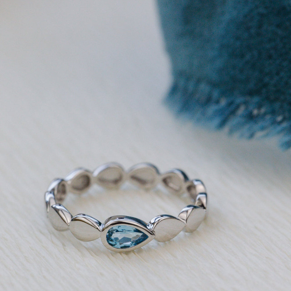 white gold ring with a blue gemstone on a light surface
