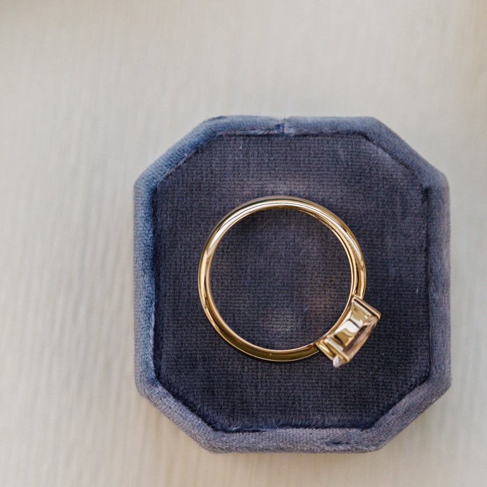 Gold ring with a diamond on a blue velvet cushion