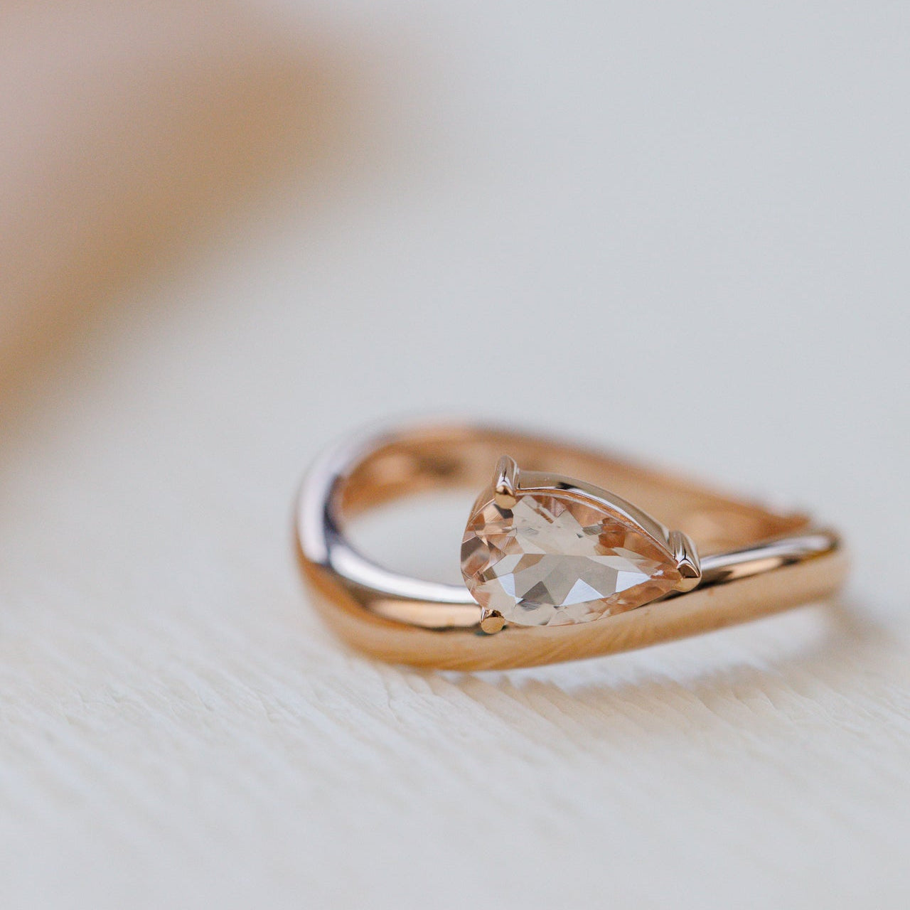 Rose gold ring with a clear gemstone on a light background