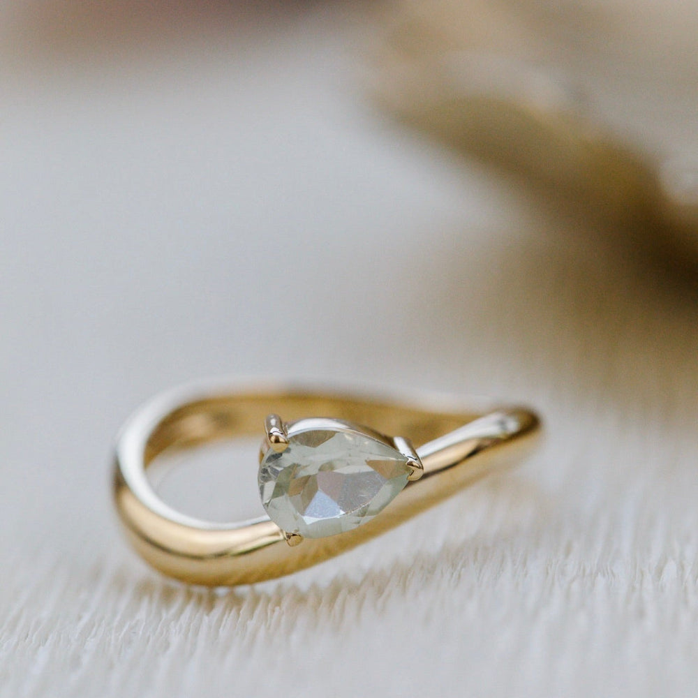 Gold ring with a green gemstone on a light background