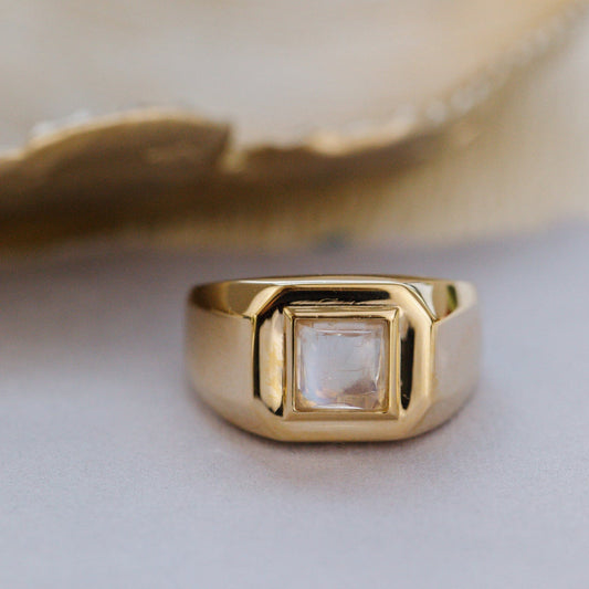 Gold ring with a clear gemstone on a light background